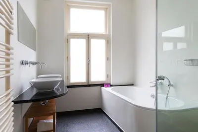 a white bathroom with a tub and a sink at Marnix360apartments Modern in Amsterdam
