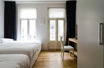 a bedroom with two beds and a desk with a chair at Marnix360apartments Design in Amsterdam