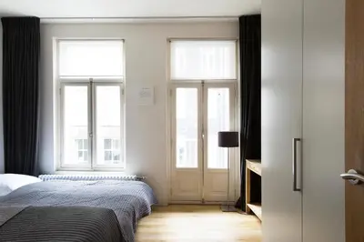 a bedroom with a bed and two windows at Marnix360apartments Design in Amsterdam