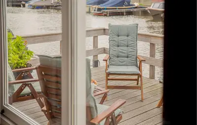 a chair sitting on a deck next to the water at Awesome Home In Breukelen in Breukelen