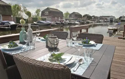 a wooden table with wine glasses and a table with boats at Awesome Home In Breukelen in Breukelen