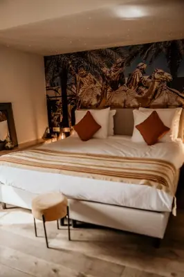 a bedroom with a large bed with a painting on the wall at Villa Beukenhof in Oegstgeest