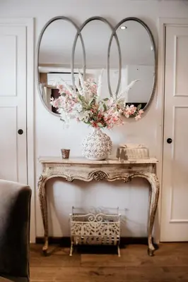 a console table with a vase of flowers and a mirror at Villa Beukenhof in Oegstgeest