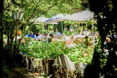 a group of people sitting at a table in a garden at Villa Beukenhof in Oegstgeest