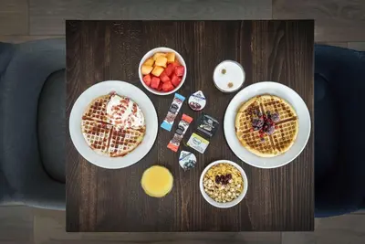 a table with two plates of waffles and bowls of fruit at Hampton by Hilton Amsterdam Centre East in Amsterdam