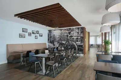 a restaurant with tables and chairs and a wall mural at Hampton by Hilton Amsterdam Centre East in Amsterdam