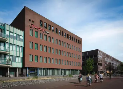 people riding bikes in front of a building at Hampton by Hilton Amsterdam Centre East in Amsterdam
