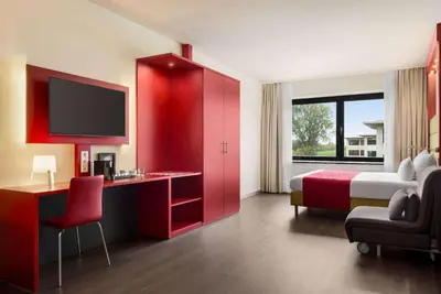 a hotel room with a bed and a red cabinet at Amedia Amsterdam Airport Schiphol, Trademark Collection by Wyndham in Schiphol