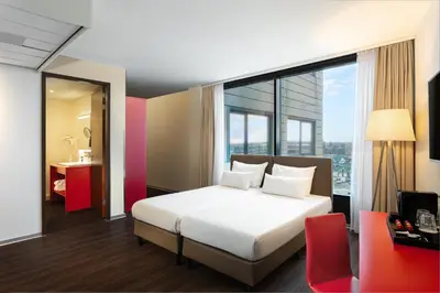 a bedroom with a white bed and a large window at Amedia Amsterdam Airport Schiphol, Trademark Collection by Wyndham in Schiphol