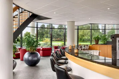 a lobby with a bar and chairs and windows at Amedia Amsterdam Airport Schiphol, Trademark Collection by Wyndham in Schiphol