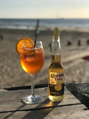 a bottle of corona beer next to a drink at Beach House Sea-Esta in Egmond aan Zee