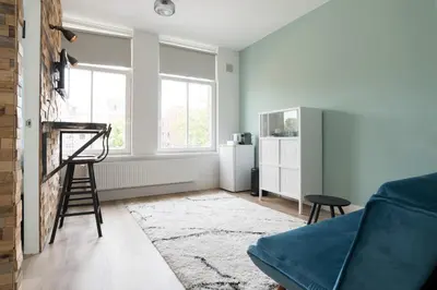 a living room with a blue couch and a chair at Happy Day´s in Amsterdam