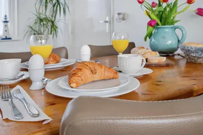 a wooden table with a breakfast of croissants and orange juice at 't Zwanennest in Egmond aan den Hoef