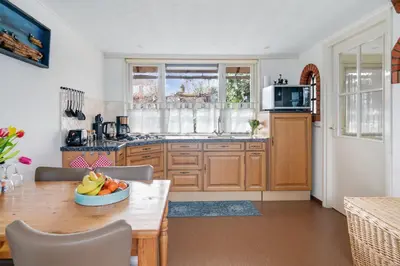a kitchen with wooden cabinets and a table with a bowl of fruit at 't Zwanennest in Egmond aan den Hoef