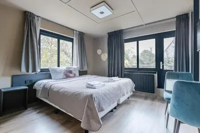 a bedroom with a bed and two blue chairs at Hotel Zee Bergen in Bergen
