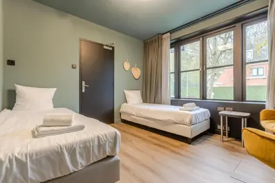 a bedroom with two beds and a window at Hotel Zee Bergen in Bergen