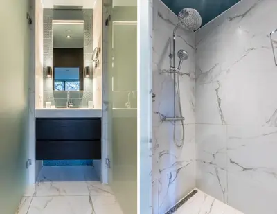 a bathroom with white marble walls and a shower and a sink at Hotel Zee Bergen in Bergen