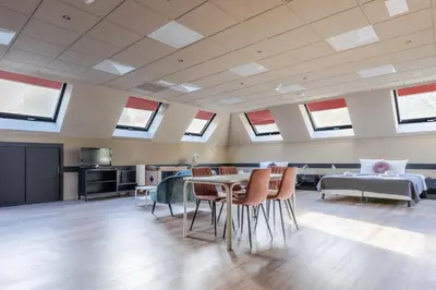 a room with a table and chairs and a bed at Hotel Zee Bergen in Bergen
