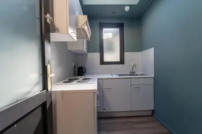a small kitchen with white cabinets and a sink at Hotel Zee Bergen in Bergen
