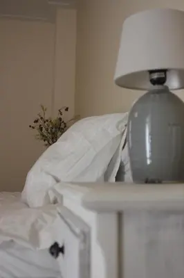 a white lamp sitting on a table next to a bed at Proeverij de Azijnmakerij in Zeist