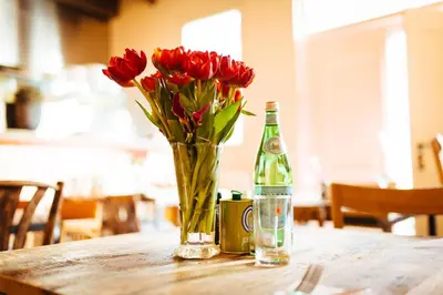 a vase of red tulips sitting on a table with a bottle at Proeverij de Azijnmakerij in Zeist