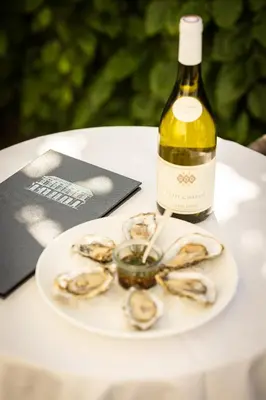 a plate of oysters and a bottle of wine at Boutique Hotel De Witte Dame in Abcoude