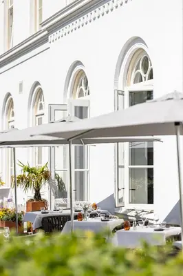 two tables with white umbrellas in front of a building at Boutique Hotel De Witte Dame in Abcoude