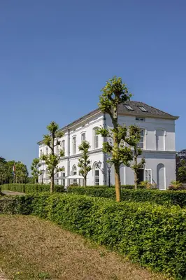 a large white building with trees in front of it at Boutique Hotel De Witte Dame in Abcoude