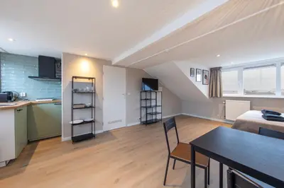 a kitchen and a living room with a table and chairs at Blankebil Studios & Apartments in Zandvoort