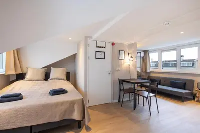 a bedroom with a bed and a table and a couch at Blankebil Studios & Apartments in Zandvoort