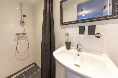 a bathroom with a sink and a shower with a mirror at Blankebil Studios & Apartments in Zandvoort