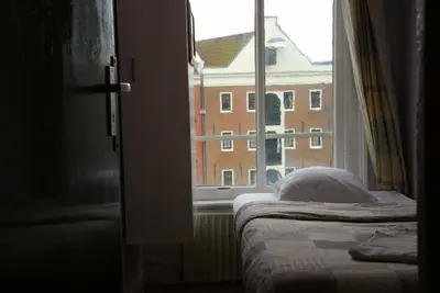 a bedroom with a bed and a window with a building at Hotel Tamara in Amsterdam