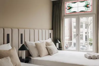 a bedroom with a large white bed with a window at Adam Suites Hotel in Amsterdam