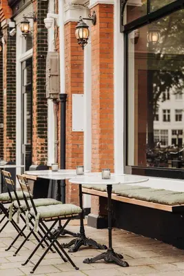 a couple of tables and chairs in front of a building at Adam Suites Hotel in Amsterdam
