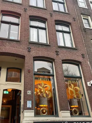 a tall brick building with windows on a street at Hotel 83 in Amsterdam