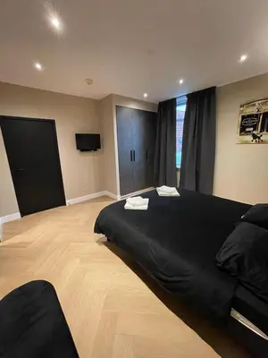 a bedroom with a large black bed and a television at Hotel 83 in Amsterdam