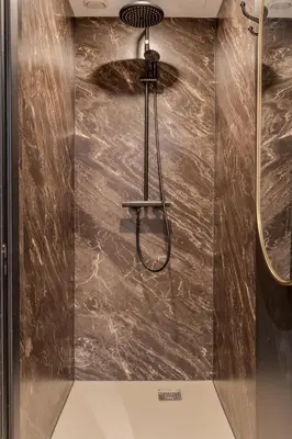a shower in a bathroom with a brown marble wall at Hotel 83 in Amsterdam