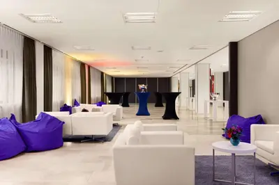a lobby with white chairs and purple furniture at NH Amsterdam Zuid in Amsterdam