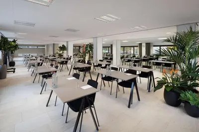 a restaurant with tables and chairs and potted plants at NH Amsterdam Zuid in Amsterdam