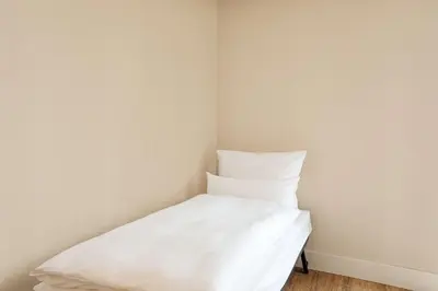 a white bed in a corner of a room at NH Amsterdam Zuid in Amsterdam