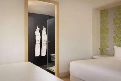 a bedroom with a closet with two beds and a mirror at NH Amsterdam Zuid in Amsterdam