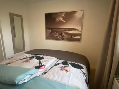 a bed in a bedroom with a picture on the wall at Apartment Ella with free privat parking in Zandvoort