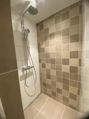 a shower with a shower head in a bathroom at Apartment Ella with free privat parking in Zandvoort