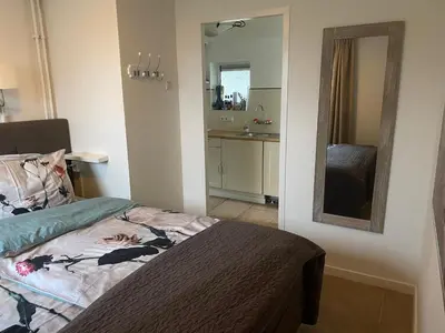 a small bedroom with a bed and a mirror at Apartment Ella with free privat parking in Zandvoort