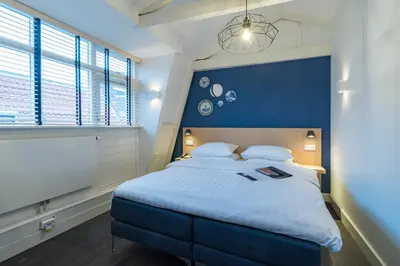 a bedroom with a large bed with a blue headboard at Amistad hotel in Amsterdam