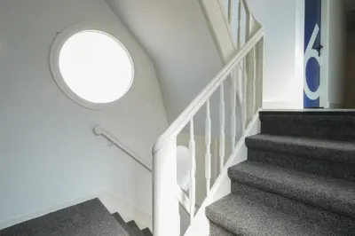 a spiral staircase with a round window in a house at Amistad hotel in Amsterdam