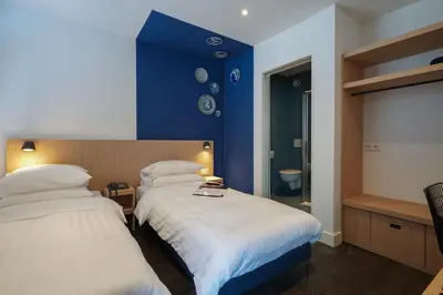 two beds in a room with a blue wall at Amistad hotel in Amsterdam