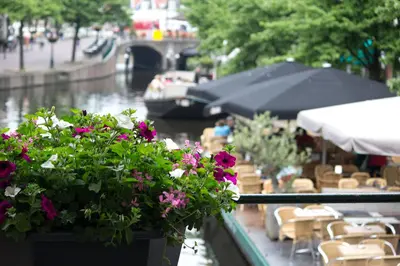 a balcony with flowers and tables and a boat at NR22 Leiden in Leiden