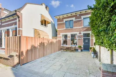 a home with a wooden fence and a patio at Cute Beach House Zandvoort in Zandvoort