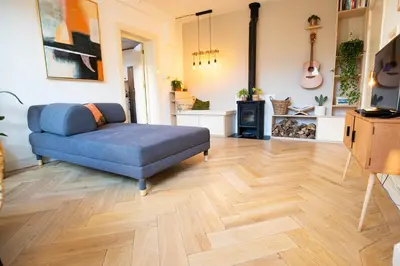 a living room with a blue couch and a wooden floor at Cute Beach House Zandvoort in Zandvoort